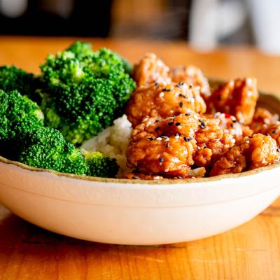 Crispy chicken rice bowl with broccoli and sesame seeds.