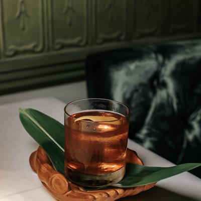 Old fashioned cocktail served in a low glass with citrus garnish on a table..