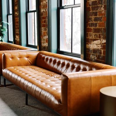 Brown tufted leather sofa against exposed brick walls and industrial windows.