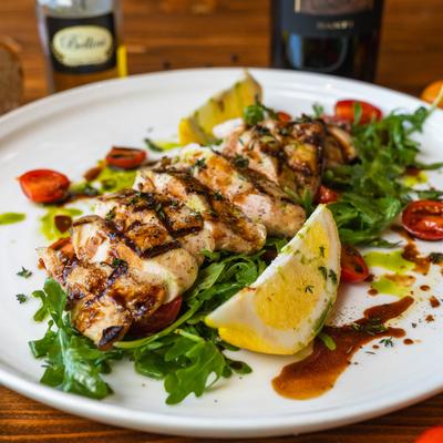 Grilled and sliced chicken with arugula, tomatoes, and lemon, side view.