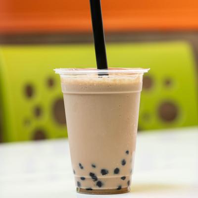 Milk Tea with boba pearls served in a plastic cup with a straw.