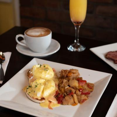 Eggs Benedict with potatoes, coffee and orange juice.
