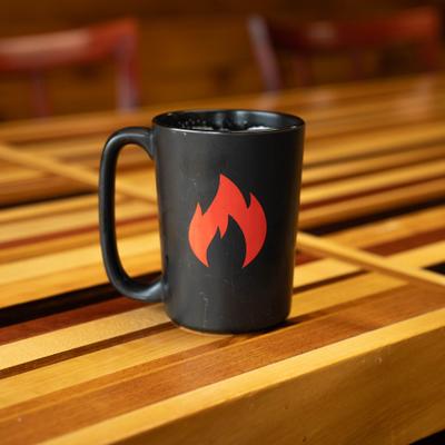 Black coffee mug featuring a red flame logo.