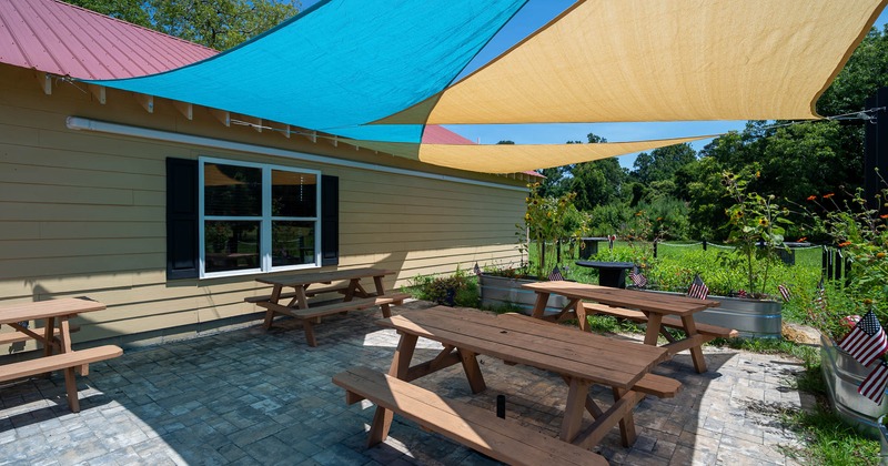 Outdoor patio with picnic tables and sunshades