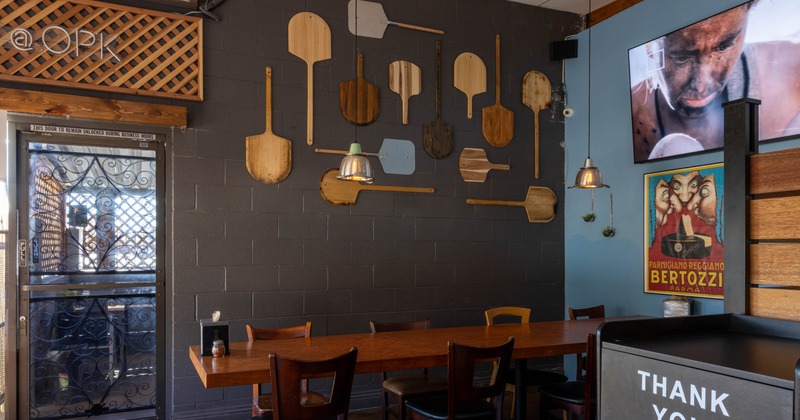Interior, dining area, wooden top table for eight, wooden chairs, pizza peels wall decoration