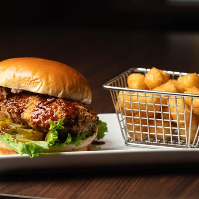 Hot honey chicken sandwich with a basket of tater tots.