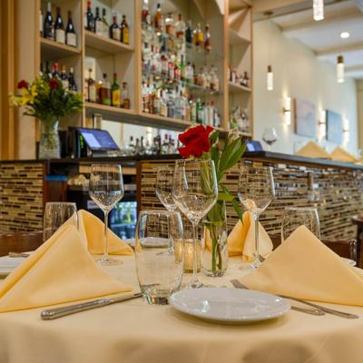 Close-up of a table set for guests with a bar in the background.
