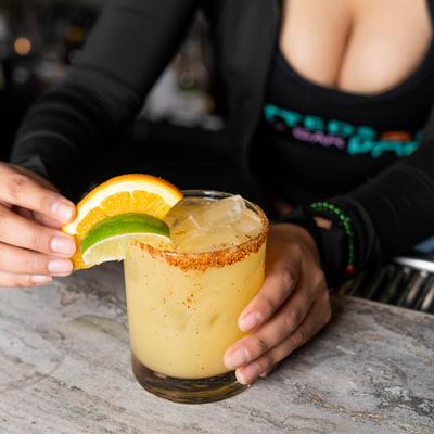 Bartender garnishes a rimmed glass of Margarita with citrus slices