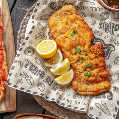 The Hayloft Massive Schnitzel served on branded paper with lemon wedges.