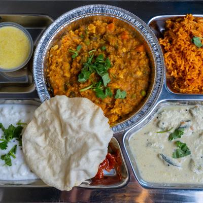 A thali meal served on a stainless steel platter.