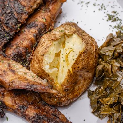 Turkey wing dinner with sides of baked potato and collard greens.