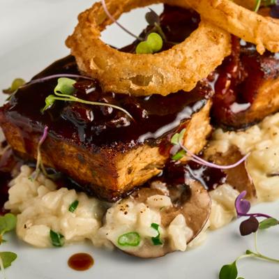 Crispy seared pork belly with wild mushroom risotto and crispy onion rings.