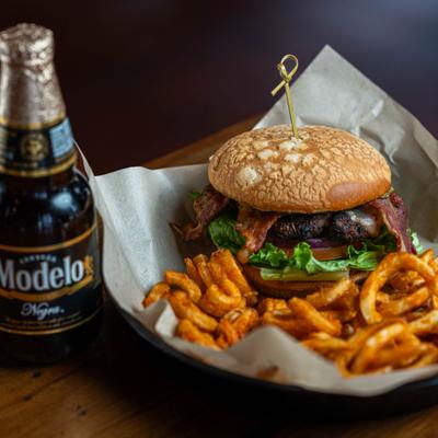 Cali Cheeseburger with curly fries, alongside a bottle of beer.