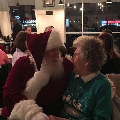 A person dressed as Santa embracing another person in a restaurant setting.