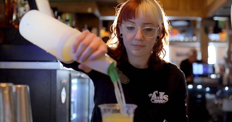 A bartender pouring a drink behind bar counter