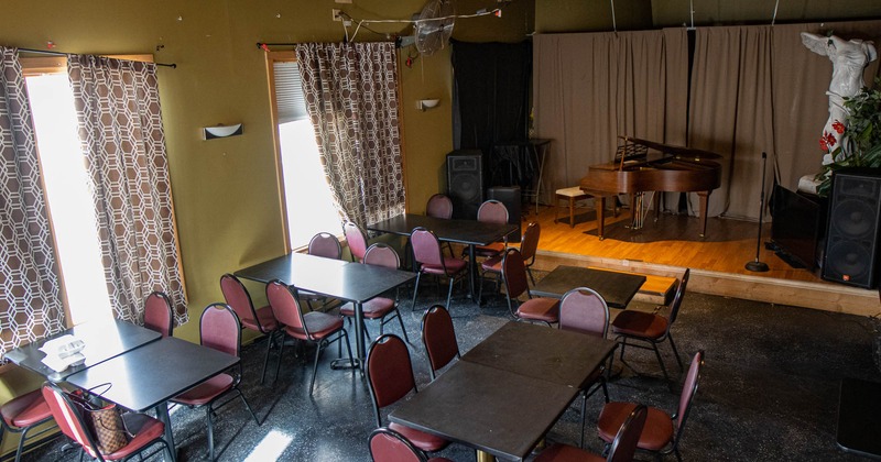 Interior, tables and chairs waiting for guests, a stage with a piano