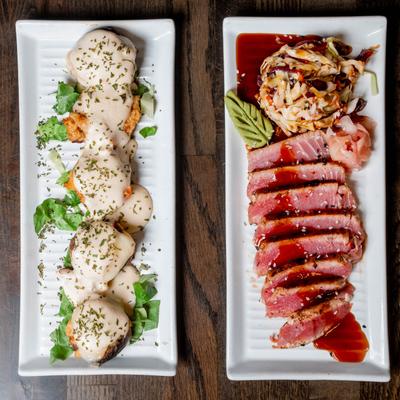 Plates of tuna tataki and crab-stuffed mushrooms on a table.