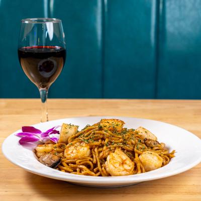 Seafood lo mein served with a glass of red wine.