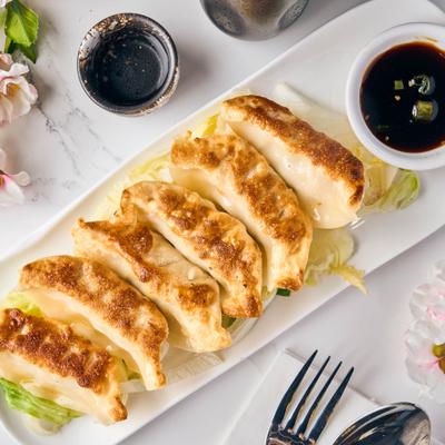 Pork dumplings arranged on a rectangular platter with soy sauce.