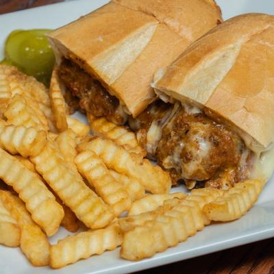 Meatball sub with crinkle cut fries on the side.