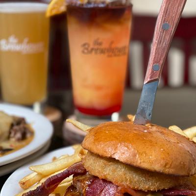 Bacon cheeseburger with onion ring cocktails in the back ground.