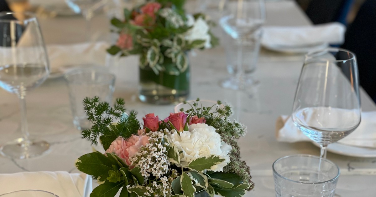 A close up view of a table with table cloth, flowers, glasses and tableware