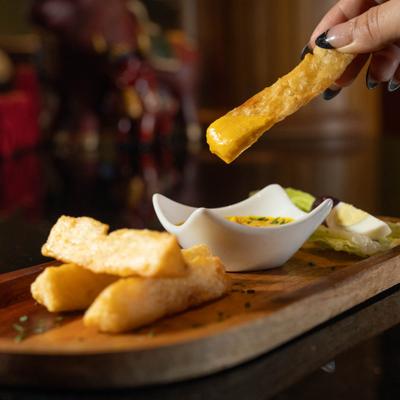 Fried yuca stick dipped into creamy yellow sauce.