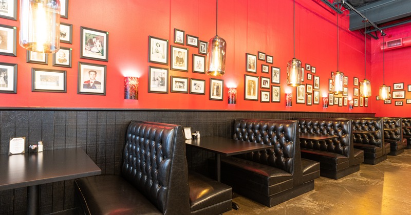 Interior, black inline booths by a red wall decorated with vintage photos