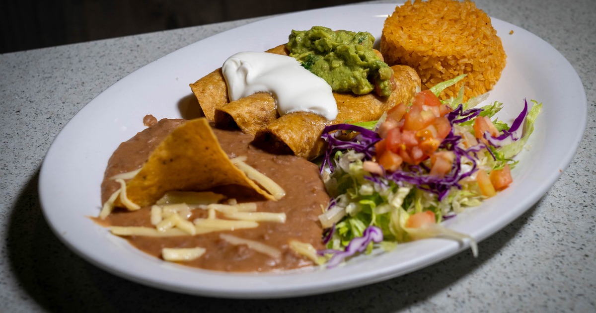 Taquitos plate accompanied with rice, beans, guacamole, sour cream