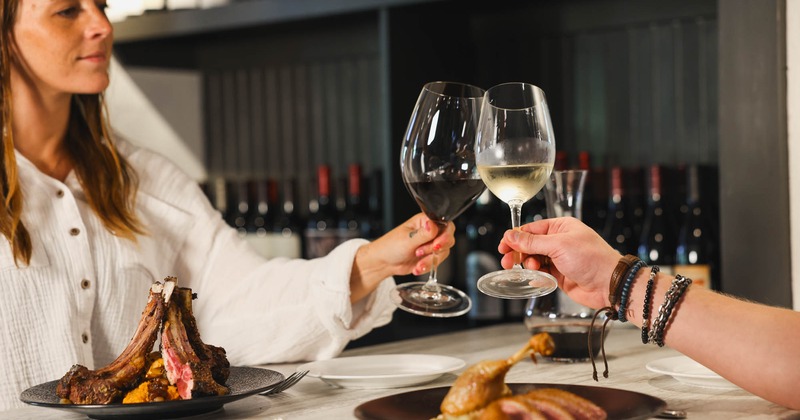 Diner table, two guests toast with wine