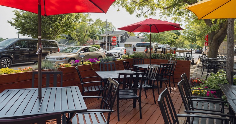 Outdoor patio with black tables and chairs, red and yellow umbrellas