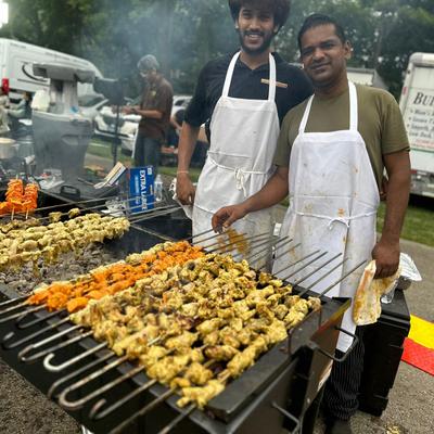 Absolute BBQ grill, two employees preparing food on skewers.