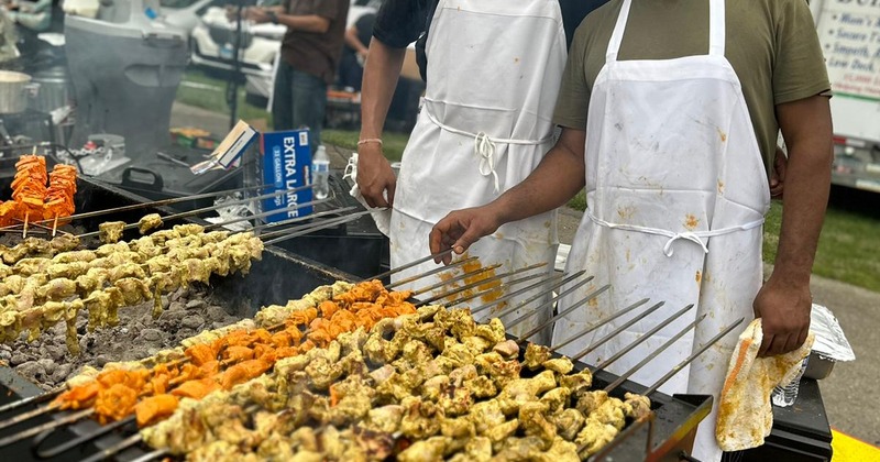 Outdoors, staff cooking food on grill skewers