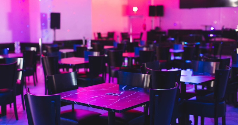 Interior, seating area, close-up of tables with pink glow cast across the room