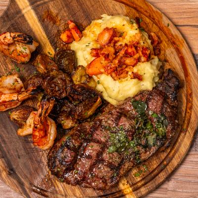 Grilled steak with mashed potatoes and shrimp, overhead view.