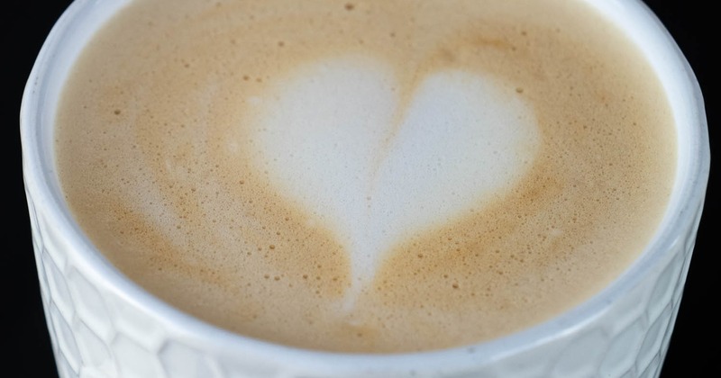 White cup of latte, set against a dark background