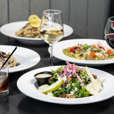 Multiple food plates and drinks spread on a table.