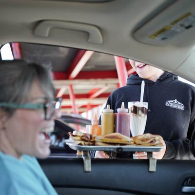 customer in car receiving tray of food.