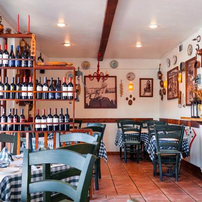 Interior with set tables, wall art, and assorted wine bottles on wooden shelves.