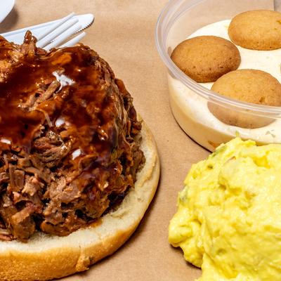 Chopped brisket sandwich with pudding and potato salad on the side.