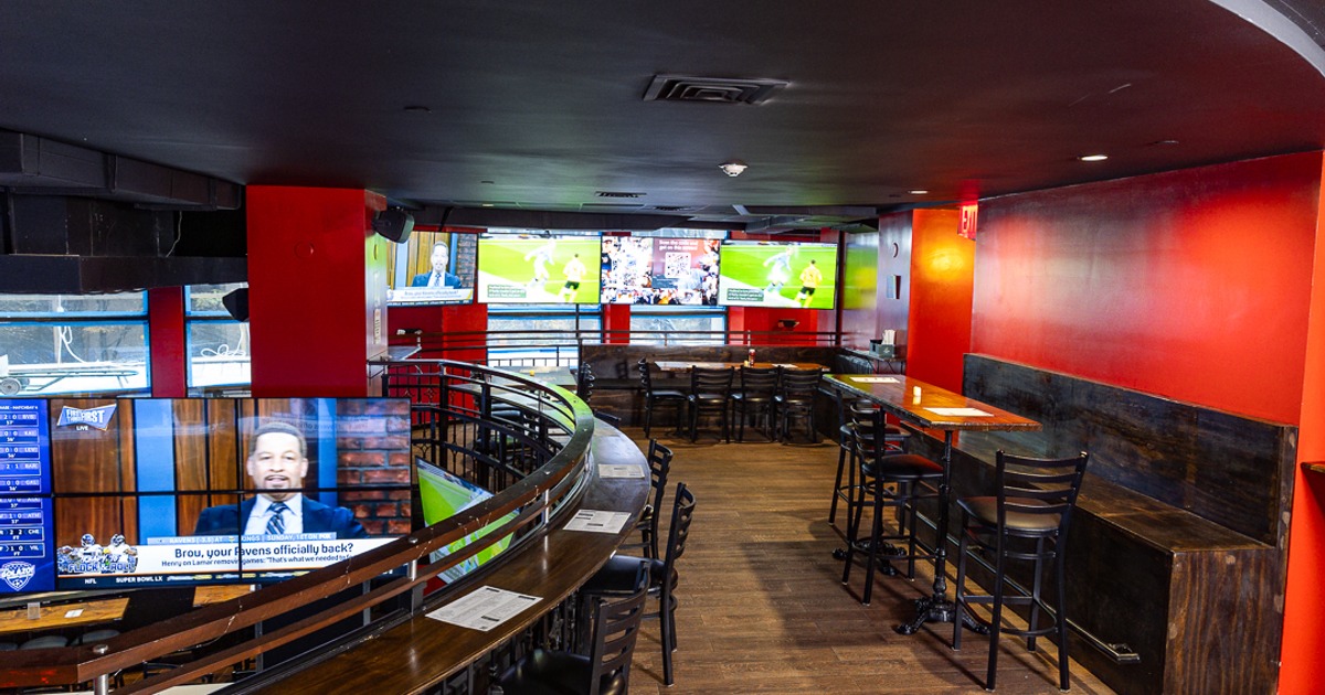 Upper level interior with curved counter seating, booths and TV screens