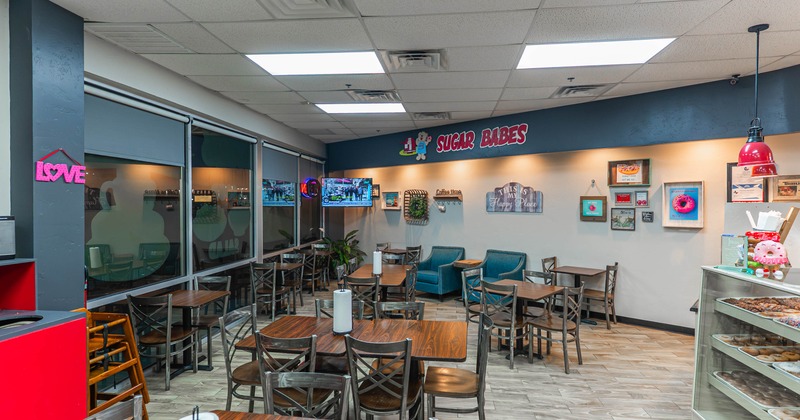 Interior of a cafe with wood tables, chairs, and a pastry display case