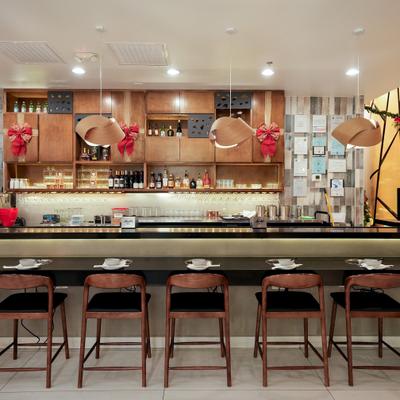 View at the bar area with a counter, stools and shelves behind the bar.