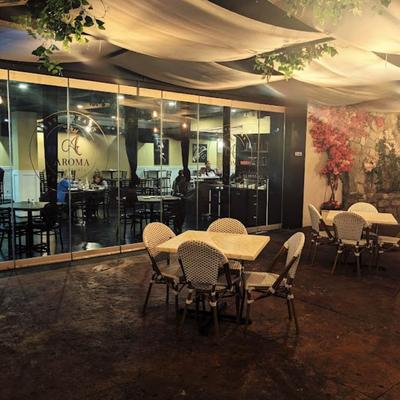 Patio with wicker chairs and tables, decorated with ceiling drapes and greenery.