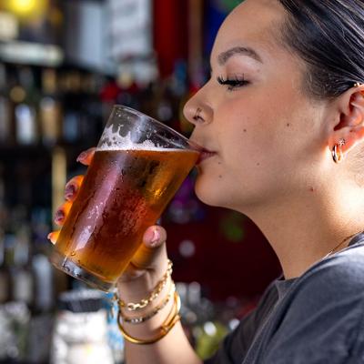 A guest takes a sip of beer at the bar.