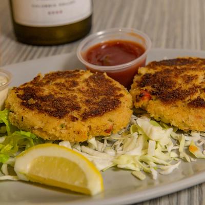 Crab cakes with sauce and a lemon wedge.