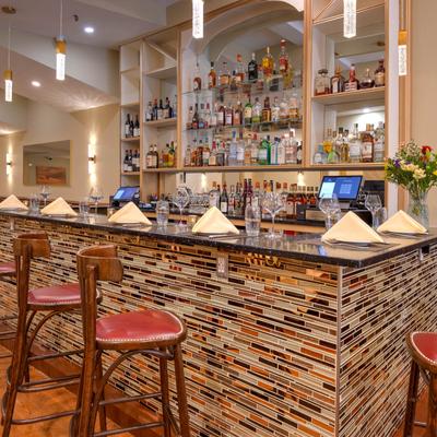 Bar set for guests with napkins and utensils, liquor bottles on the shelves behind.