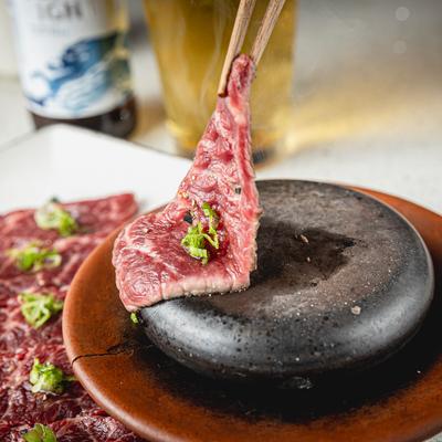Sliced kobe beef being prepared on hot rock.
