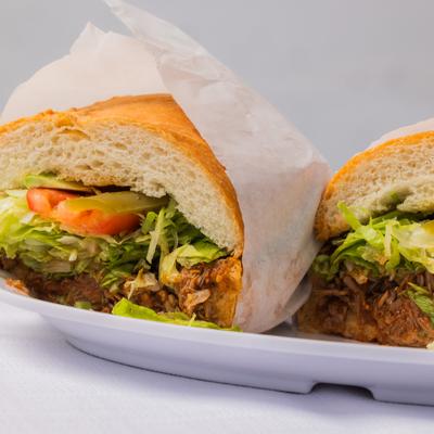 Torta De Birria with lettuce, tomato and peppers.