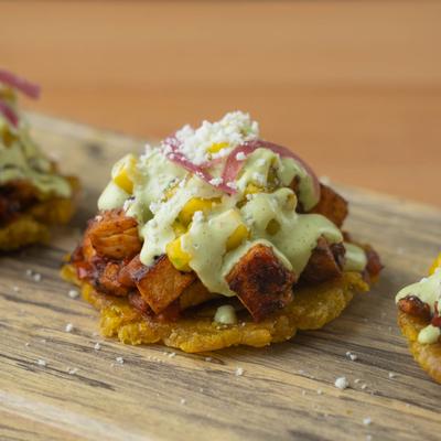 Fried green plantains topped with chicken and mango sauce.